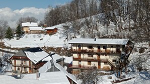 Un village enneigé, avec ses maisons traditionnelles en bois, une église et une chaîne de montagnes en arrière-plan.