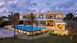 Una casa moderna de dos pisos amb piscina, zona d'estar a l'aire lliure i pati ben il·luminat.