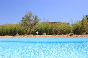 Una piscina cristallina con una sponda rocciosa e vegetazione rada.