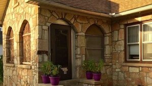 A stone house with a front door, two windows, and two potted plants on the porch. - Hunterston Cottage -Sleeps 6 - Ft. Sill, Wichita Mountains, Casinos (Lawton)