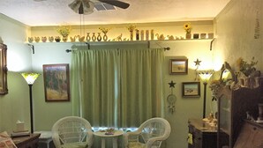 A cozy room with a bed, two chairs, a small table, a dresser, and a ceiling fan. - Hunterston Cottage -Sleeps 6 - Ft. Sill, Wichita Mountains, Casinos (Lawton)