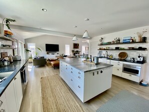 A modern kitchen with a central island, white cabinetry, and a dining area with a sofa and coffee table.