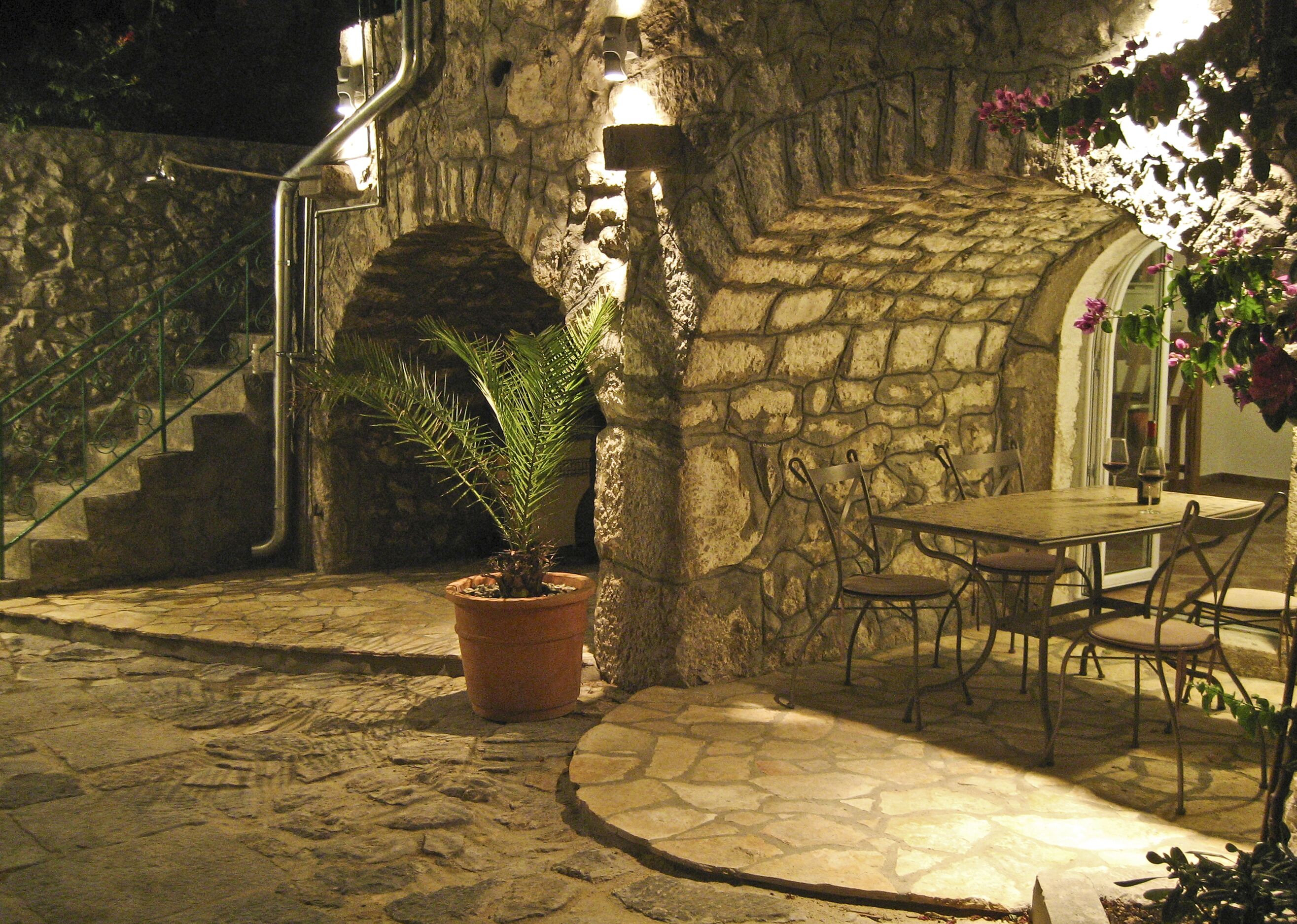 A stone building with a staircase, a table with chairs, and a potted plant.