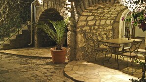 A stone building with a staircase, a table with chairs, and a potted plant.