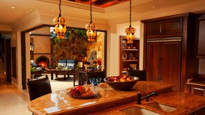 Una cocina amplia con una isla grande, una chimenea de piedra y armarios de madera.