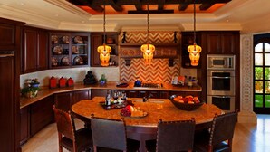 Una cocina con una isla grande, armarios de madera oscura e iluminación colgante.