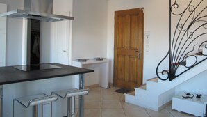 Una cocina moderna con una campana extractora de acero inoxidable, una puerta de madera y un adorno metálico en la pared.