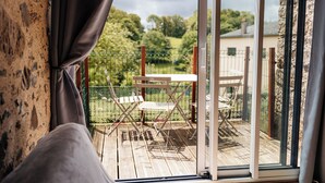 A balcony with a wooden deck, metal chairs, and a table. - Cottage 7 people near Puy du Fou (Sèvremont)