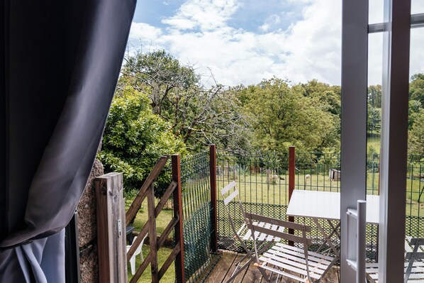 Un balcon donnant sur un paysage verdoyant et des arbres.