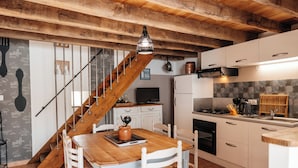 A kitchen with white cabinets, a wooden staircase, and a tiled floor. - Cottage 7 people near Puy du Fou (Sèvremont)