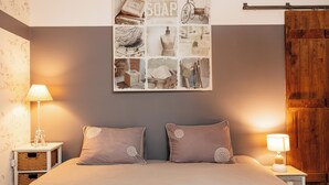A bedroom with a large bed, two bedside tables, a wall-mounted artwork, and a wooden wardrobe. - Cottage 7 people near Puy du Fou (Sèvremont)