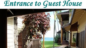 An entrance to a guest house with a stone pathway, wooden steps, and a view of the ocean.