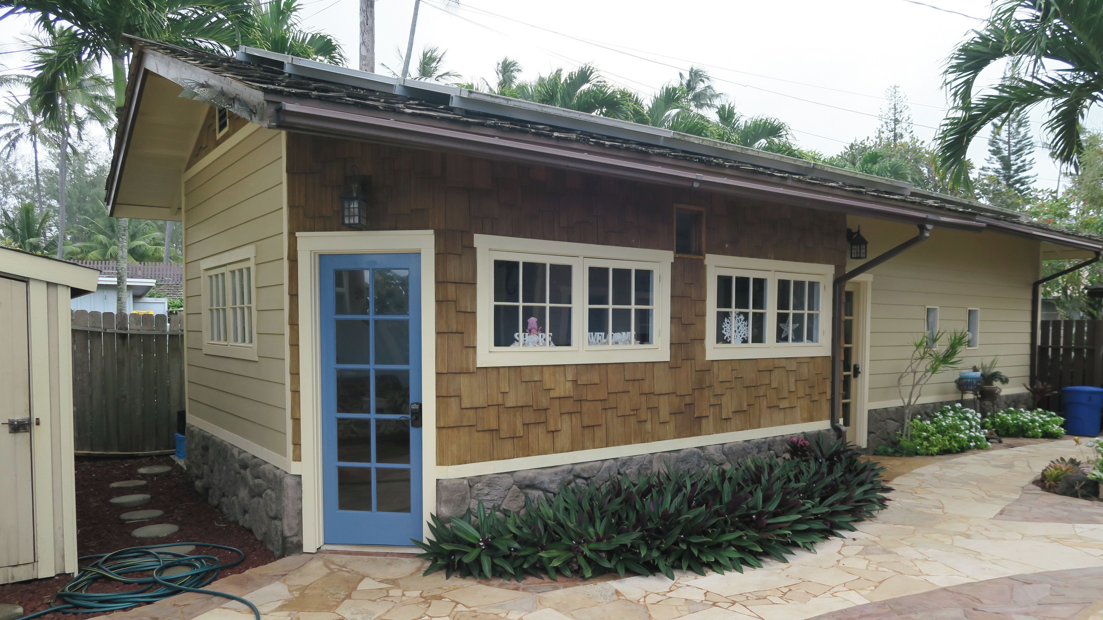 A building with an extra bedroom, a stone pathway, and a wooden fence.