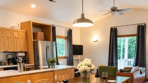 A modern kitchen with wooden cabinets, a stainless steel refrigerator, and a dining area with a wooden table and chairs. - Spacious Open-Concept Durham Home (Durham)