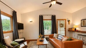 A living room with a sofa, a rocking chair, a coffee table, a ceiling fan, a TV, and a window with curtains. - Spacious Open-Concept Durham Home (Durham)