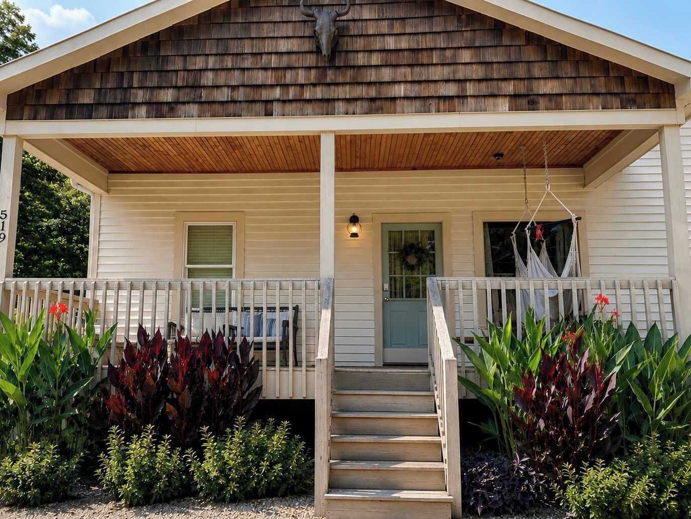 A wooden cabin with a porch, steps, and a door.