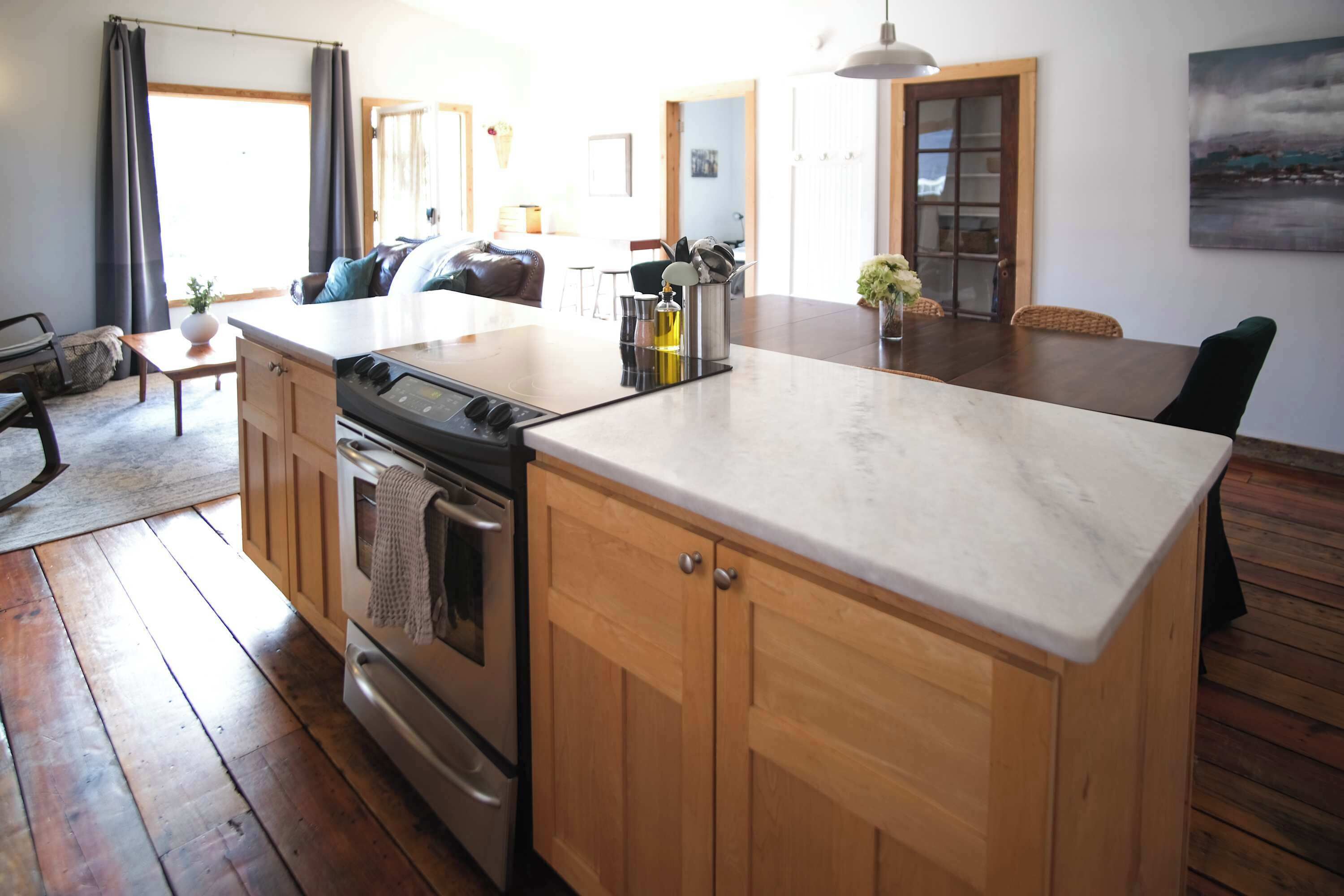 A kitchen with wooden cabinets, a central island, and a dining area with a table and chairs.