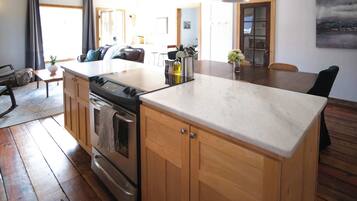 A kitchen with wooden cabinets, a central island, and a dining area with a table and chairs.