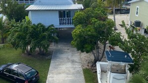 A residential area with a house featuring a large dome roof, a paved driveway, and a boat docked nearby. - Conch House on a Quiet Canal : Monthly Only (Little Torch Key)