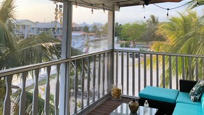 A covered balcony with a ceiling fan, a view of a waterway, and outdoor seating. - Conch House on a Quiet Canal : Monthly Only (Little Torch Key)
