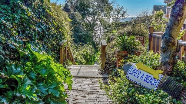 Un sendero que conduce a una zona de playa, con un letrero que dice 'LIFE'S A BEACH'.