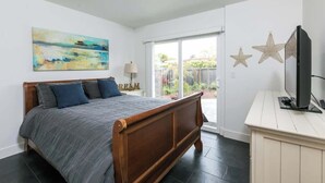 Un dormitorio con una cama de madera, un cuadro en la pared y un televisor sobre un mueble.