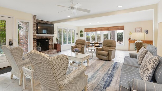 A spacious living room with a fireplace, comfortable seating, and large windows offering a view of the outdoors.