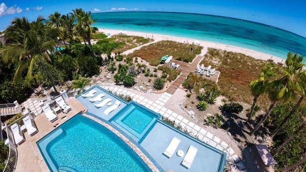A resort with two swimming pools, a beach, and palm trees.