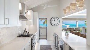 A modern kitchen with white cabinetry, a large island, and a view of the ocean.