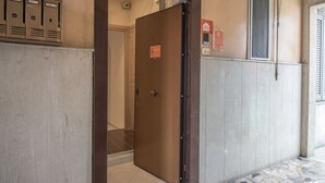 A hotel entrance with a wooden door, a coat rack, and a fire alarm box on the wall. - Casa Vacanze Carolina 348 (Naples)