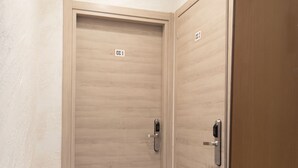 A hallway with two wooden doors, each marked with a number. A fire extinguisher is visible on the left. - Casa Vacanze Carolina 348 (Naples)