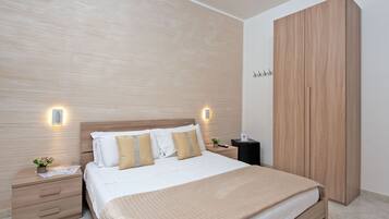 Un dormitorio ordenado con cabecera de madera, un armario amplio y mesitas de noche con lámparas.