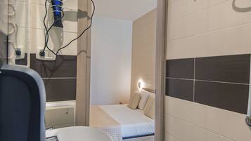 Une salle de bain équipée d’un lavabo, d’un miroir et d’un sèche-cheveux.