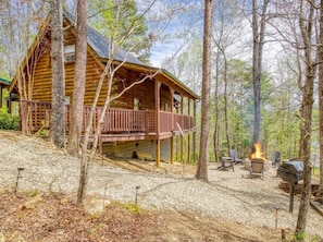 A log cabin with a balcony, surrounded by trees, and a fire pit with outdoor seating. - Secluded with Mountain View, fire pit and Private Hot tub-Pet Friendly (Sevierville)