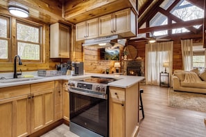 A wooden cabin interior with a kitchen, dining area, and living room. - Secluded with Mountain View, fire pit and Private Hot tub-Pet Friendly (Sevierville)
