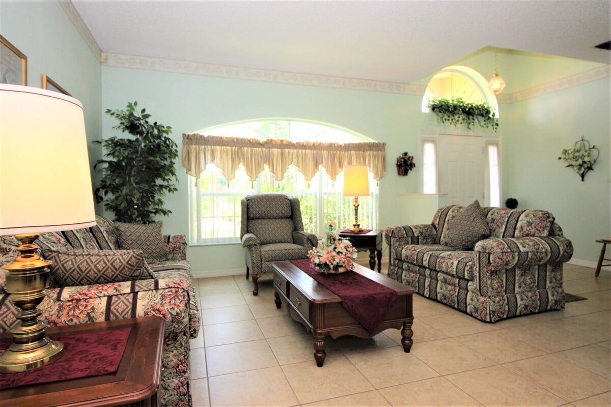 A living room with a sofa, armchair, and a table with a lamp.