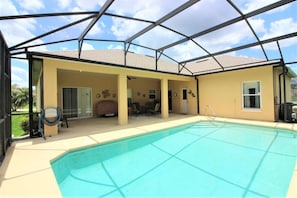 A covered outdoor swimming pool area with a patio, seating, and a view of the sky. - Huge Home in Quiet Crescent Lakes - CL001 (Kissimmee)