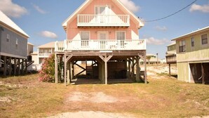 A two-story house with a balcony, a covered porch, and a wooden deck. - Peach on the Beach - 3BR/2 BA - Fort Morgan - Pet Friendly (Gulf Shores)