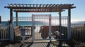 Une entrée privée menant à la plage, avec une terrasse en bois et une pergola.