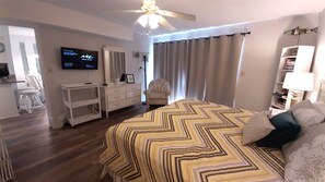 A hotel room with a bed, a desk, a chair, a television, and a bookshelf.