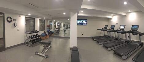 Un gimnasio con cintas de correr, mancuernas y equipo de ejercicio.