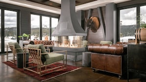 A modern living room with a fireplace, leather furniture, and large windows offering a view of the outdoors.