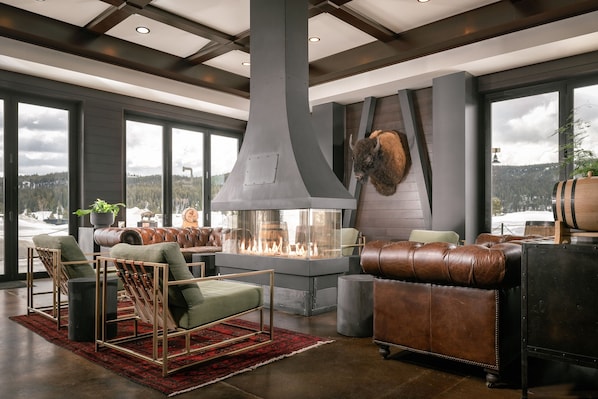 A modern living room with a fireplace, leather furniture, and large windows offering a view of the outdoors. - Residence Inn by Marriott Big Sky/The Wilson Hotel (Big Sky)