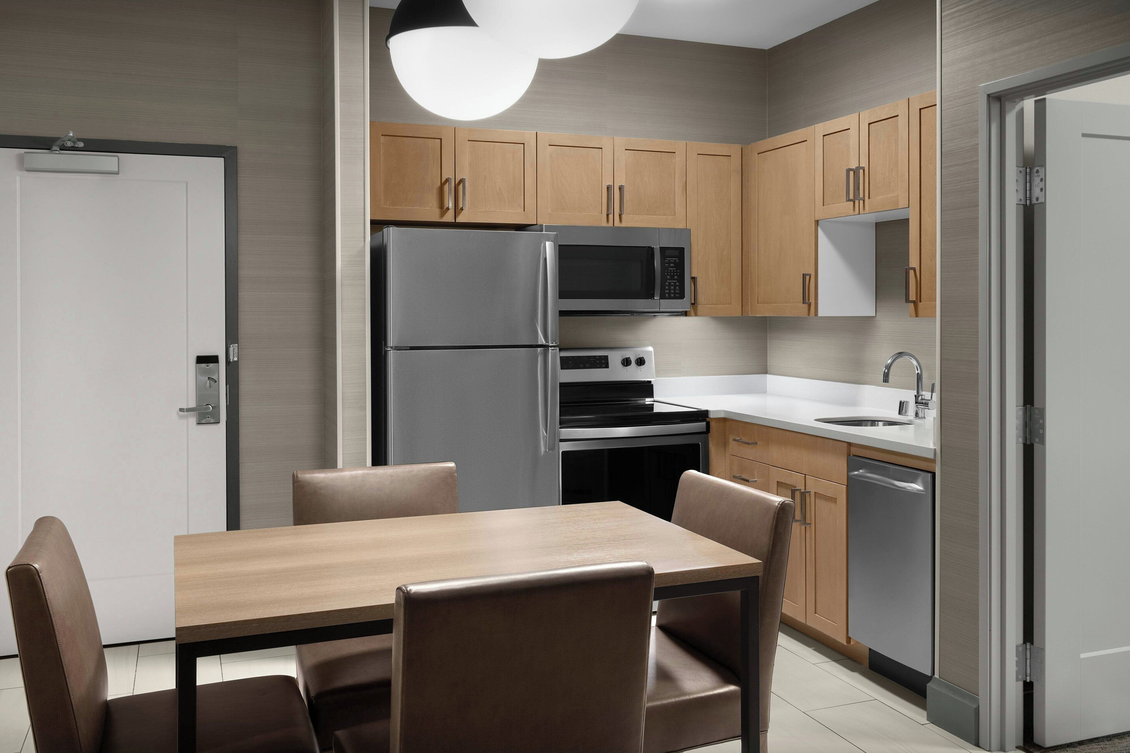 Una cocina moderna con electrodomésticos de acero inoxidable, armarios de madera y un comedor con mesa y sillas.