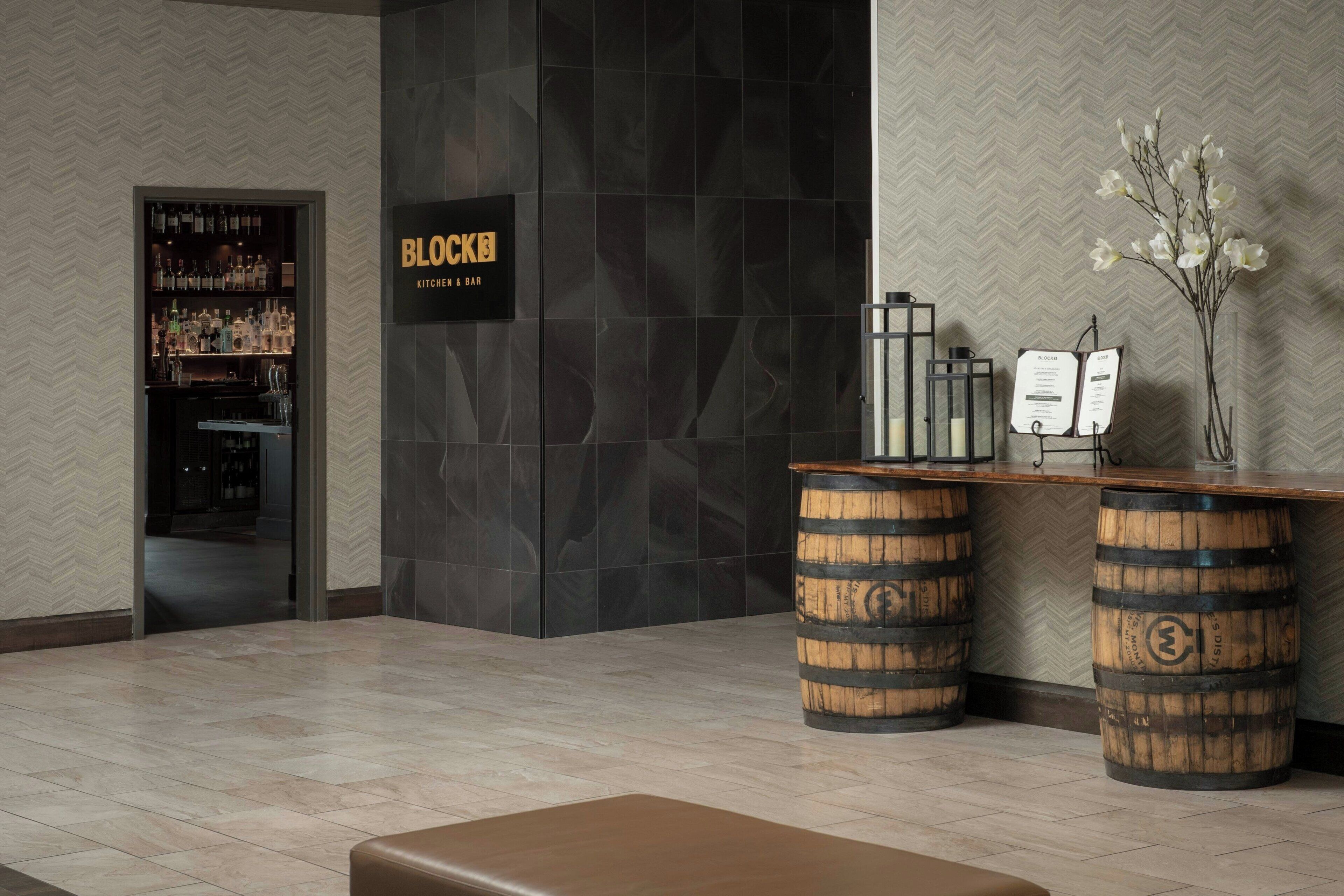 Un espace d’accueil avec un bar, des tonneaux en bois et une enseigne indiquant « BLOCKER KITCHEN & BAR ».