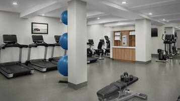 Un gimnasio moderno con cintas de correr, balones de ejercicio y máquinas de pesas.