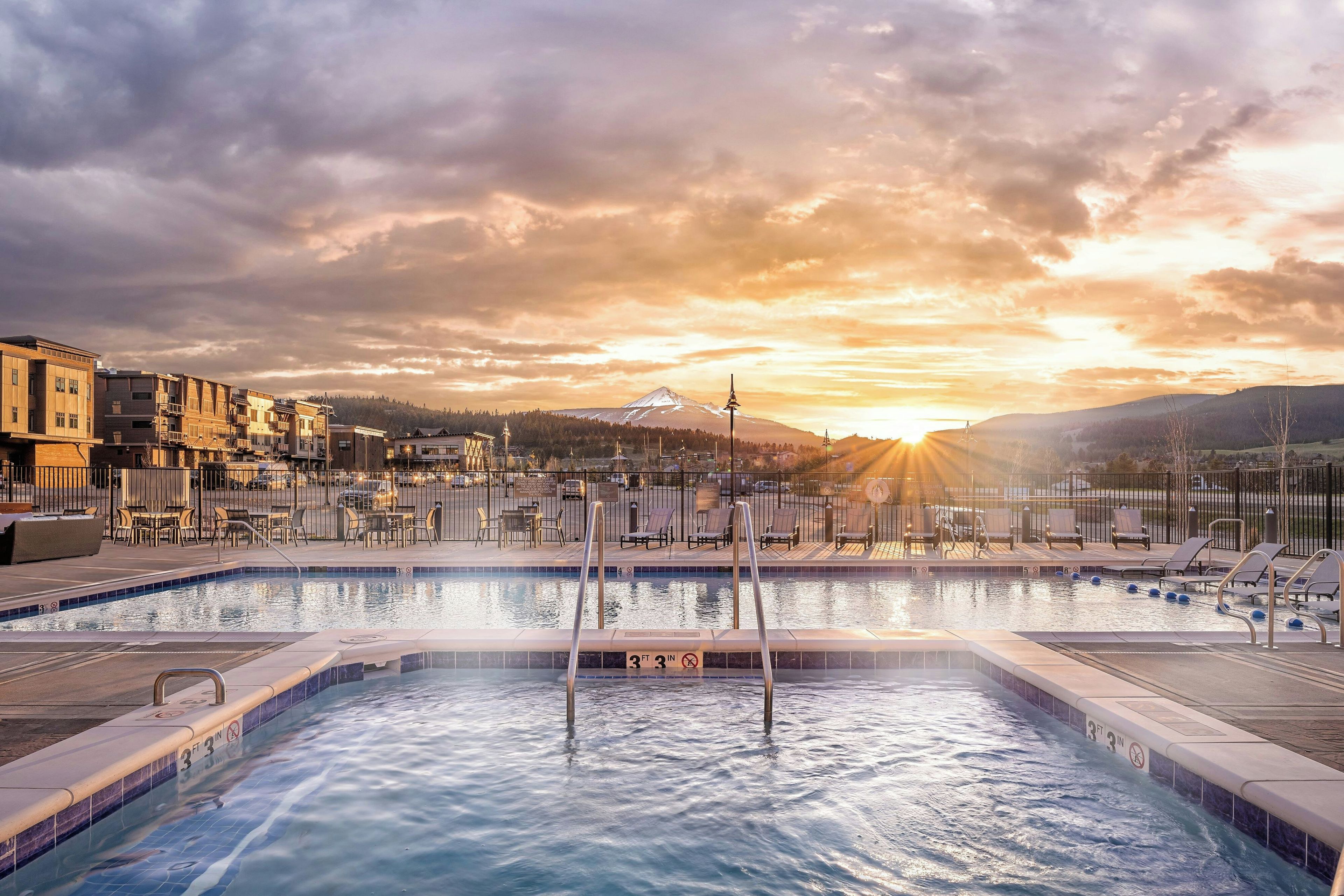 A swimming pool with a view of a mountain and a sunset.