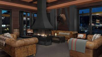 A modern living room with leather sofas, a large fireplace, and large windows offering a city view.