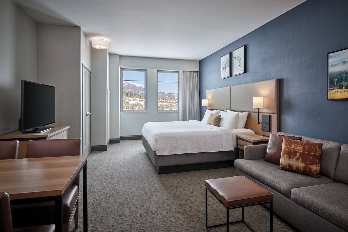 A hotel room with a bed, a sofa, a TV, and a desk.
