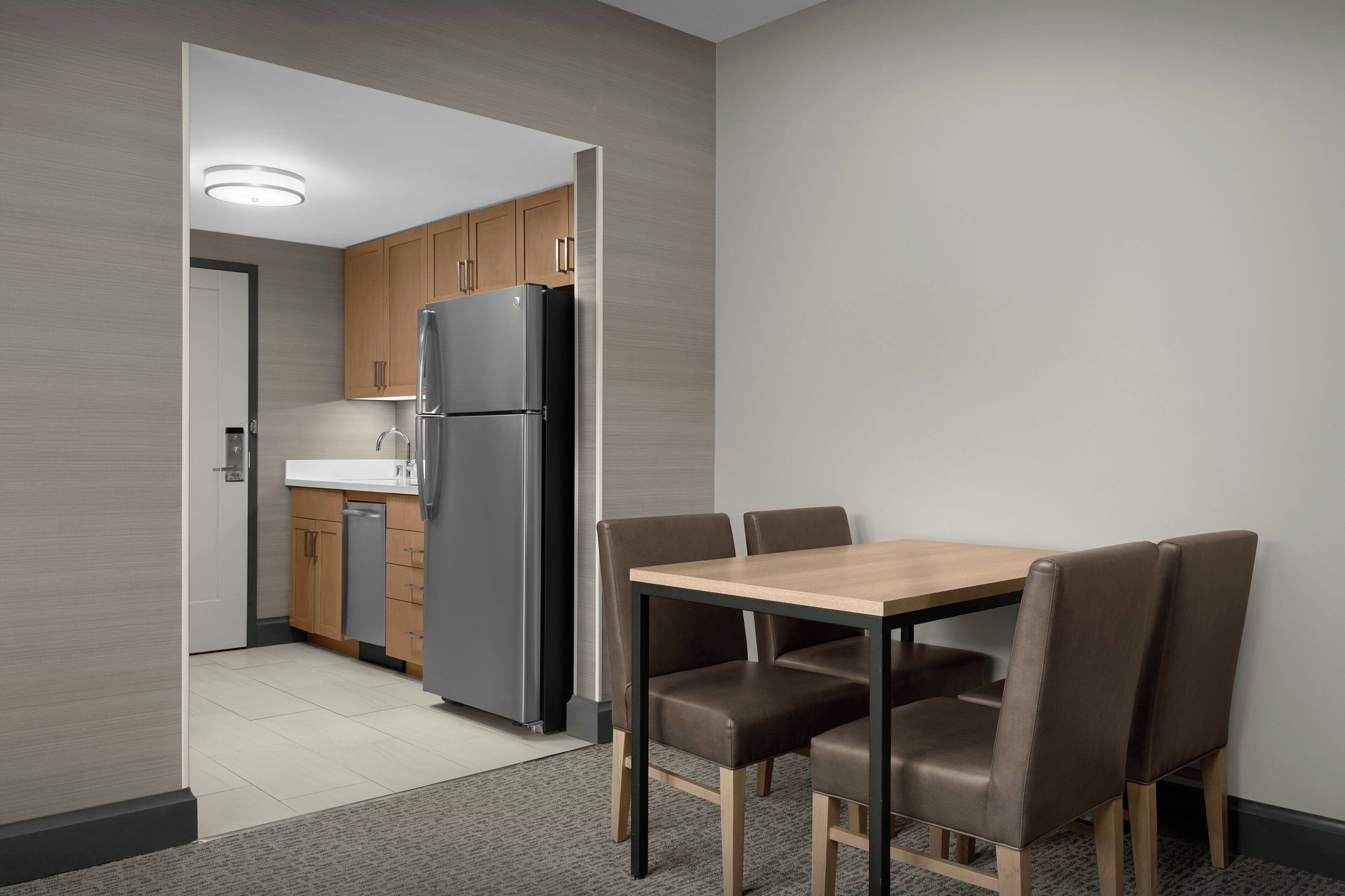 Una cocina moderna con armarios de madera, un refrigerador de acero inoxidable y una mesa de comedor con seis sillas.